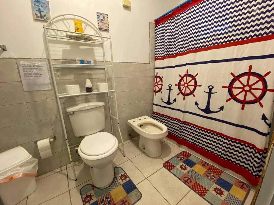 a bathroom with a toilet and an american flag shower curtain at Villa Retiro R in Boquerón Area in Cabo Rojo