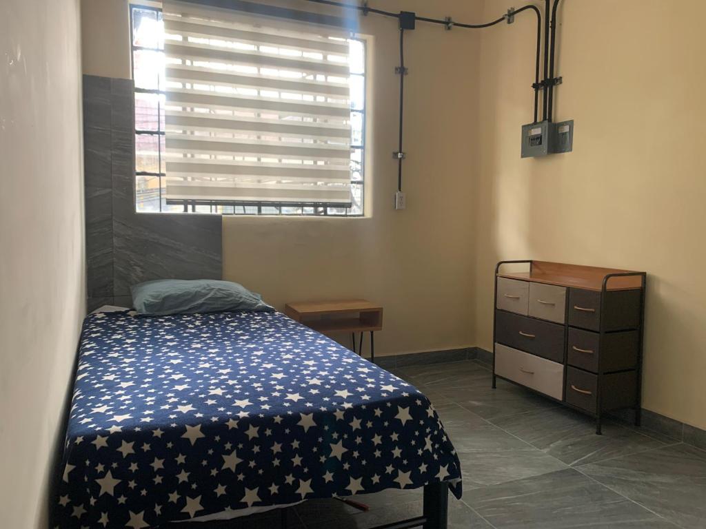 a bedroom with a bed and a dresser and a window at Hostal YOA Suite 101 in Mexico City