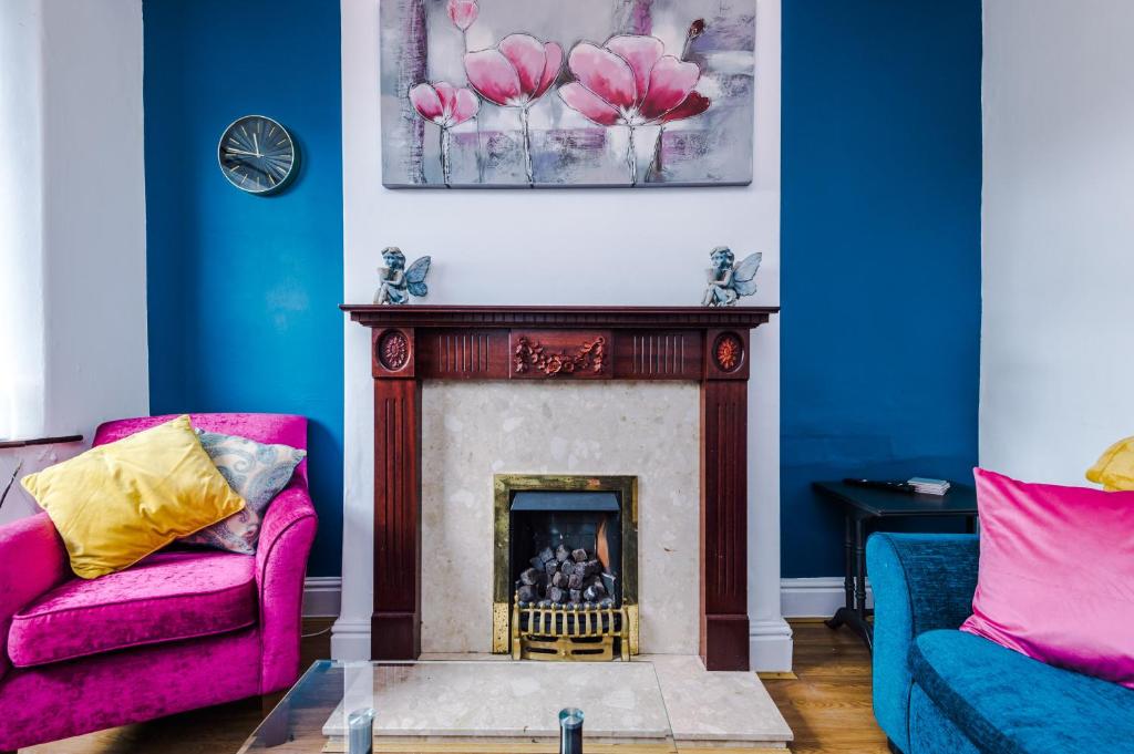 a living room with a fireplace and pink chairs at Cosy 2 Bedroom house-Short drive from Blackpool Pleasure Beach in Blackpool