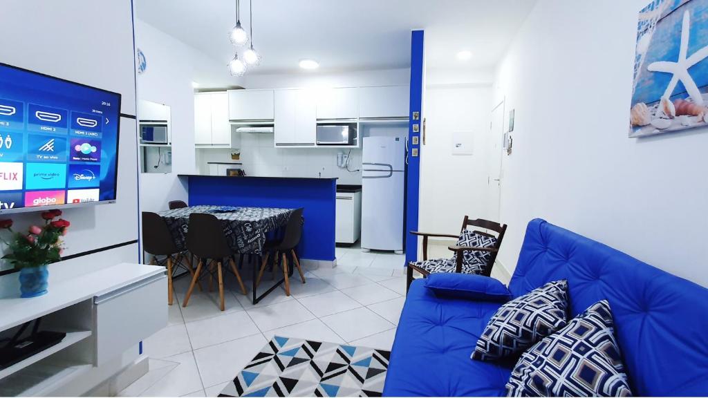 ein Wohnzimmer mit einem blauen Sofa und einer Küche in der Unterkunft Apartamento 1 Novíssimo e Bem Localizado - Itaguá - UBATUBA-SP in Ubatuba