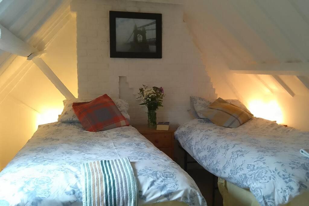 een slaapkamer met 2 bedden en een vaas met bloemen bij Cosy cottage+ secluded garden in Kent