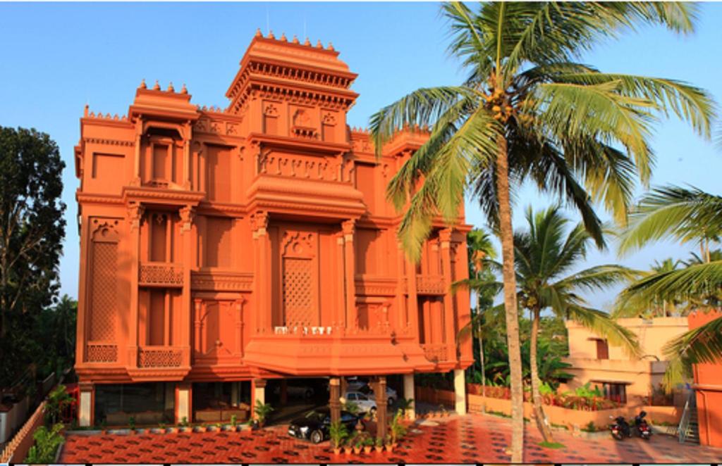 een oranje gebouw met een palmboom ervoor bij Oxygen Resorts, Alleppey in Alleppey