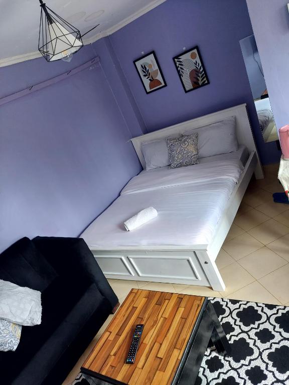 Dormitorio pequeño con cama blanca y paredes moradas en Jeda Homey Homes Studio Apartment, en Bomet