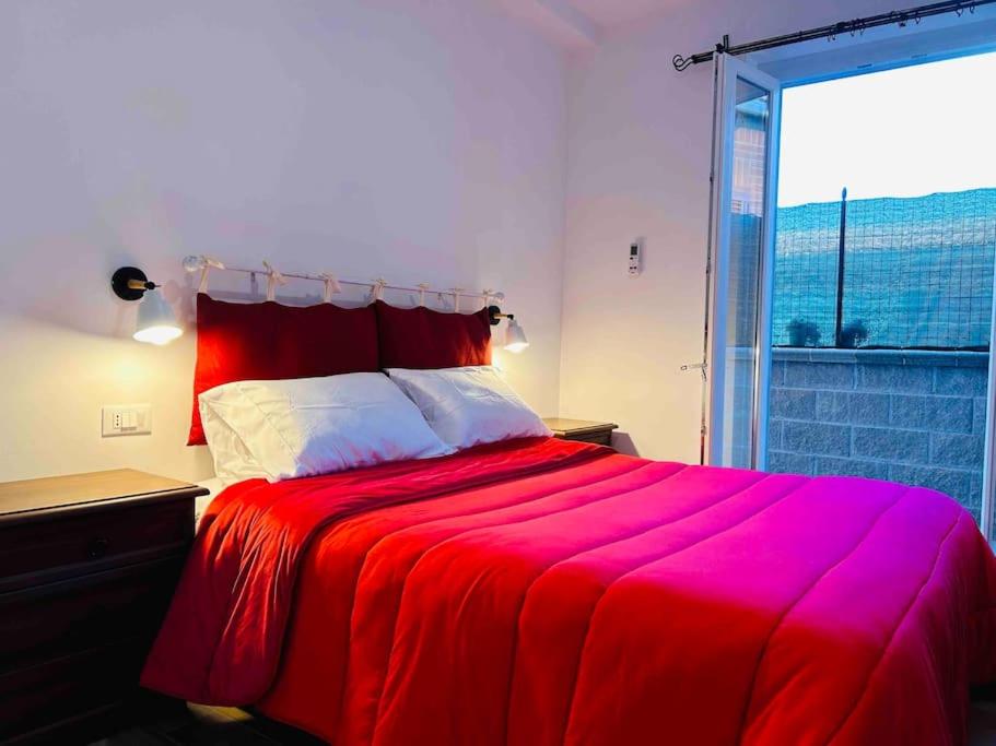 Cama roja en habitación con ventana grande en Infinity room, en Cerreto Alto