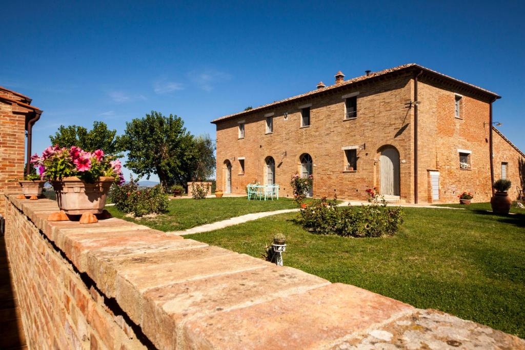 a brick building with a brick wall and flowers at Il Giardino in Asciano