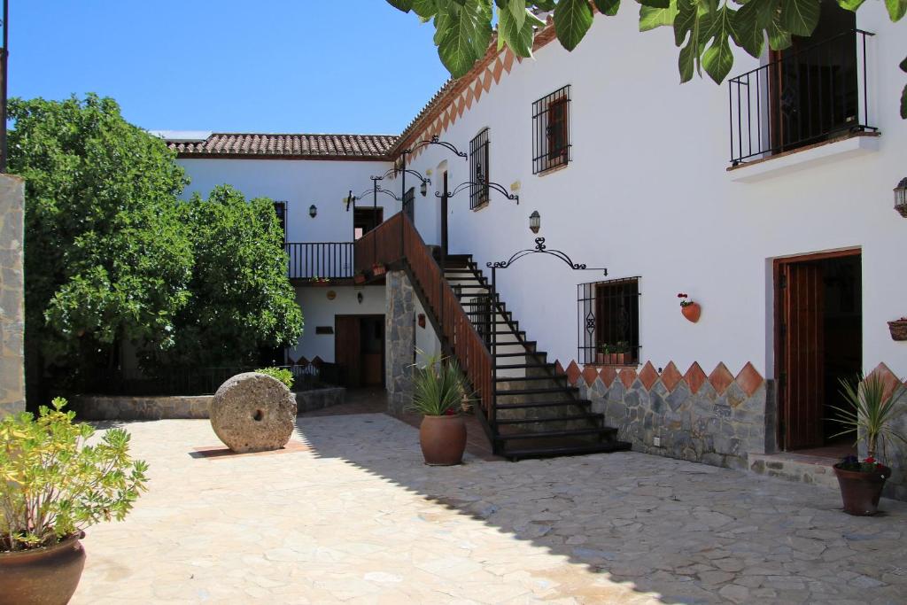 a white building with a staircase in a courtyard at Ronda Nomads in Benaoján