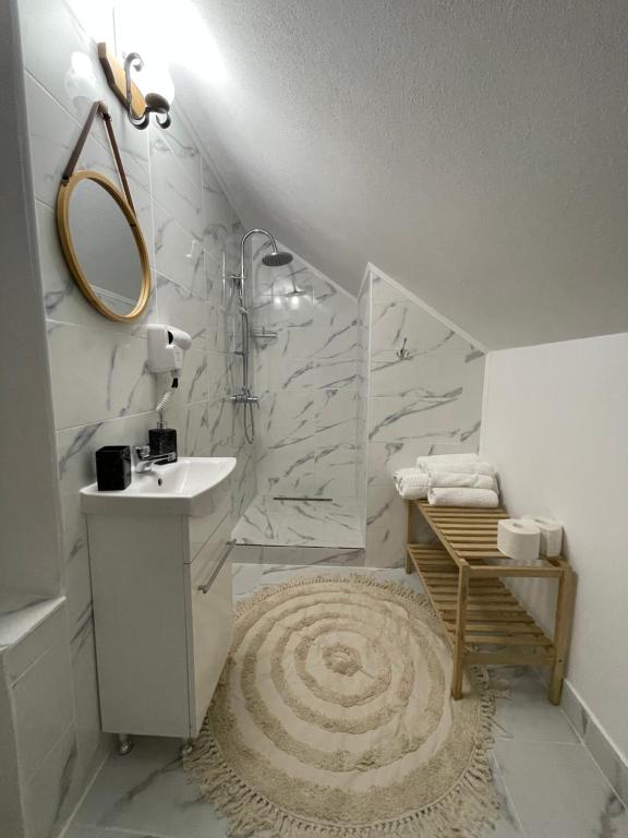 a white bathroom with a sink and a mirror at Casa Ella Maldaresti in Măldăreşti