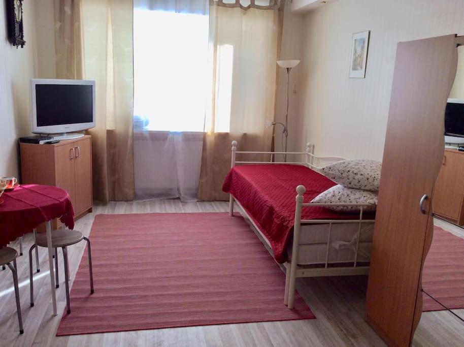 - une chambre avec un lit doté d'une couverture rouge et d'une télévision dans l'établissement Cozy studio apartment, à Tallinn