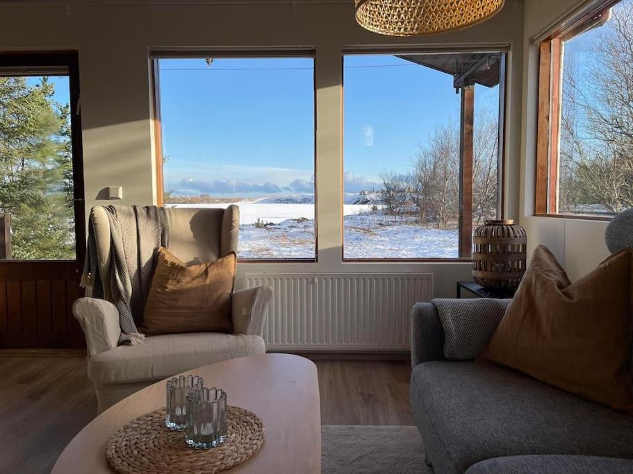 a living room with two chairs and a table and windows at Lakeview cabin near Kirkjubaejarklaustur in Kirkjubæjarklaustur
