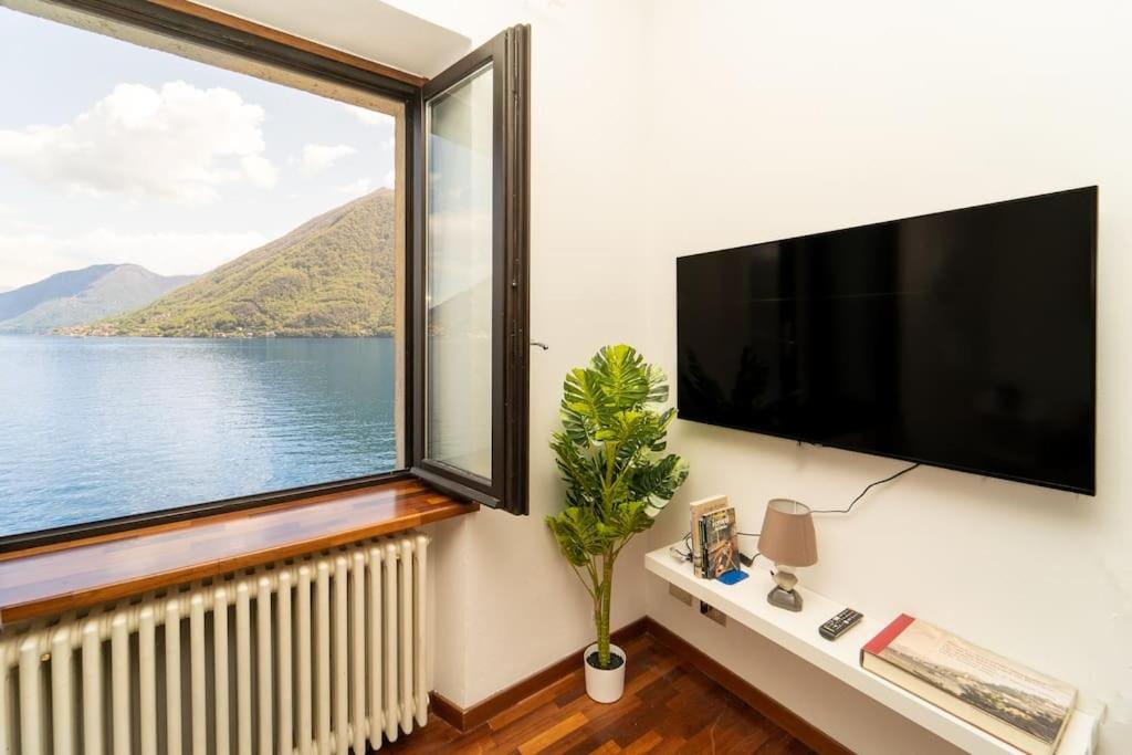 Cette chambre dispose d'une grande fenêtre et d'une grande télévision à écran plat. dans l'établissement Rustico con idromassaggio vista lago, à Brienno