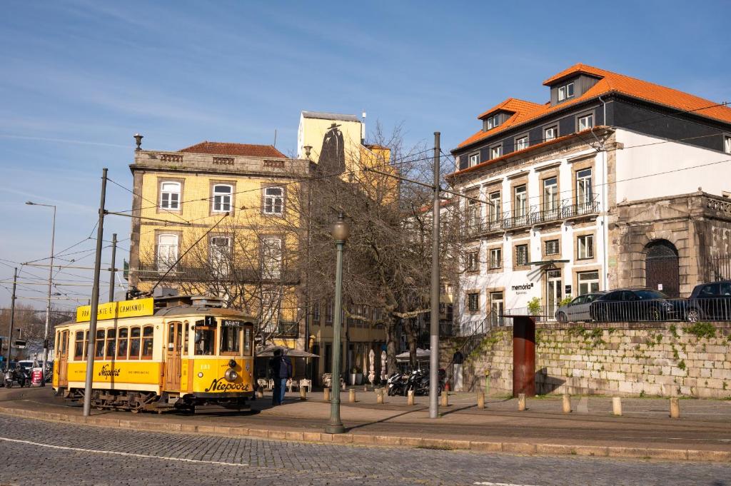 a yellow trolley on a city street with buildings at Memoria Porto FLH Hotels in Porto