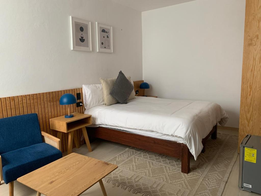 a small bedroom with a bed and a blue chair at CHOLULA SUITES in Cholula