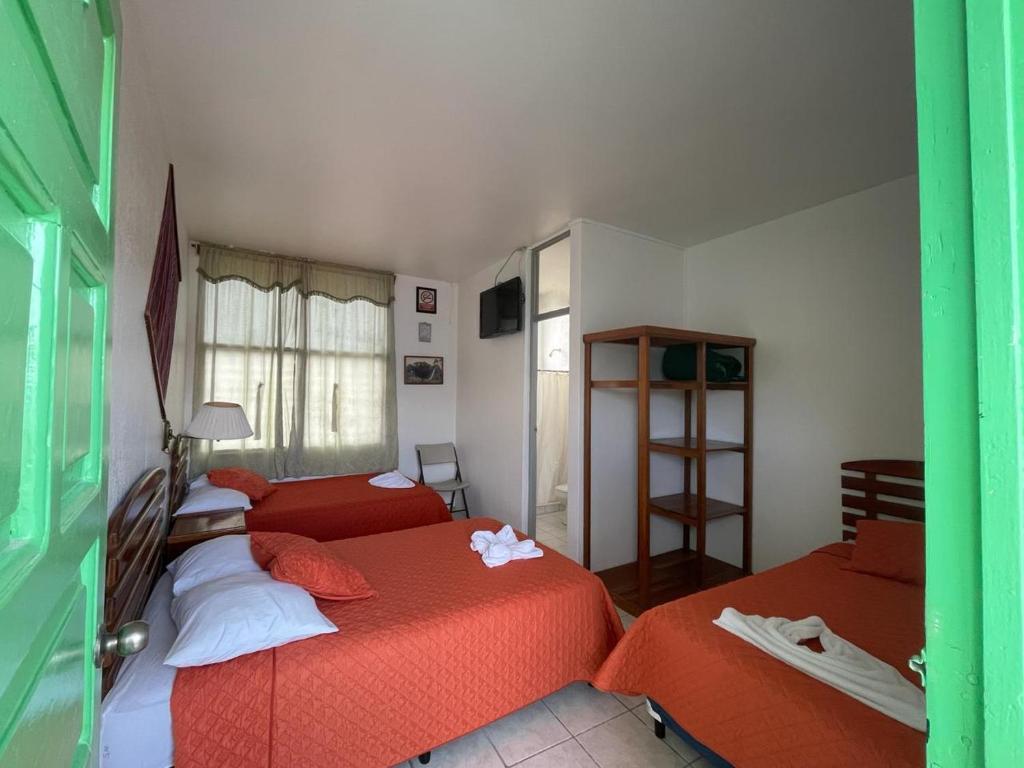 a bedroom with two beds with red sheets at Hotel Sabana in Flores