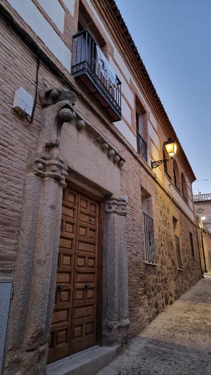 a building with a wooden door and a balcony at Dama Apartamentos Turísticos Toledo in Toledo