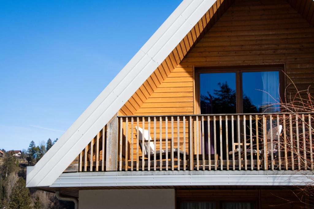 a house with a balcony with two chairs on it at Apartma Bazilika in Topolšica