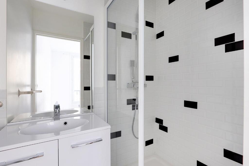 une salle de bain blanche avec un lavabo et une douche dans l'établissement studio cosy jules Joffrin, à Paris