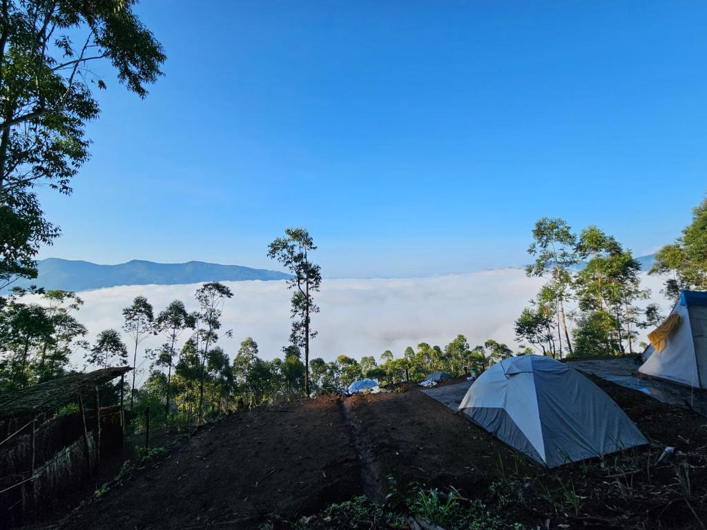 two tents on top of a hill with clouds in the background at Cloud Camping. in Munnar