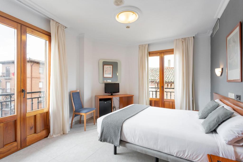 a bedroom with a bed and a desk and a window at Alda Ciudad de Toro in Toro