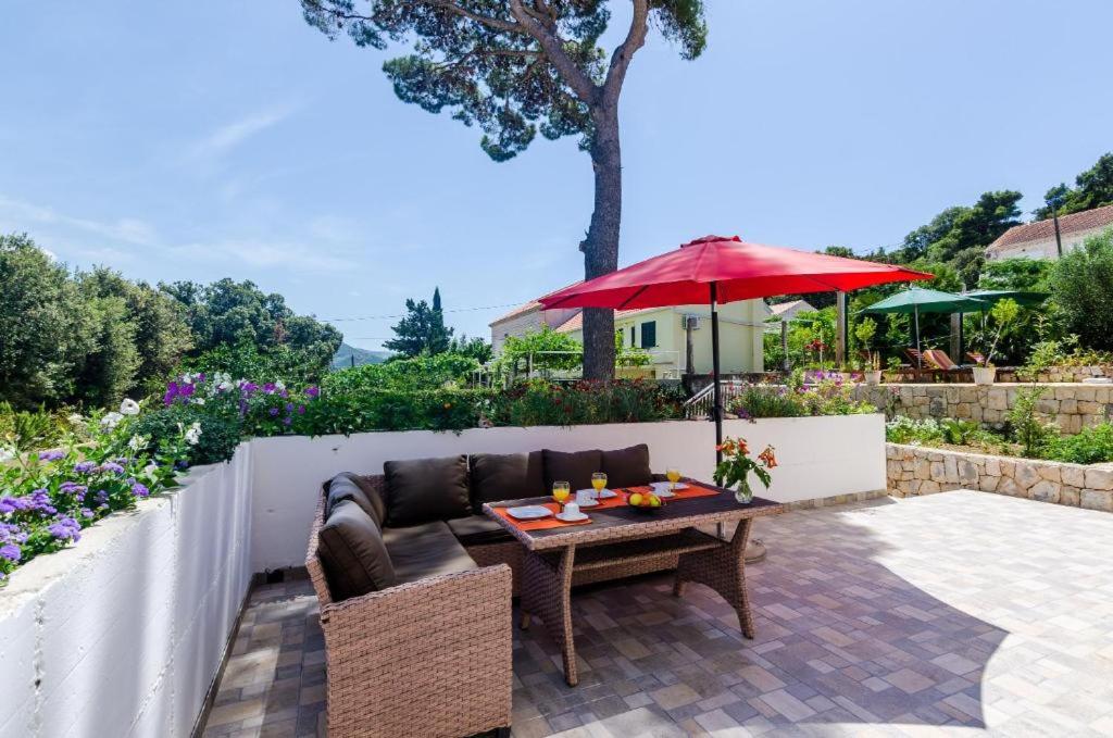 eine Terrasse mit einem Tisch und einem roten Regenschirm in der Unterkunft Apartment Maurora Terrace in Zaton