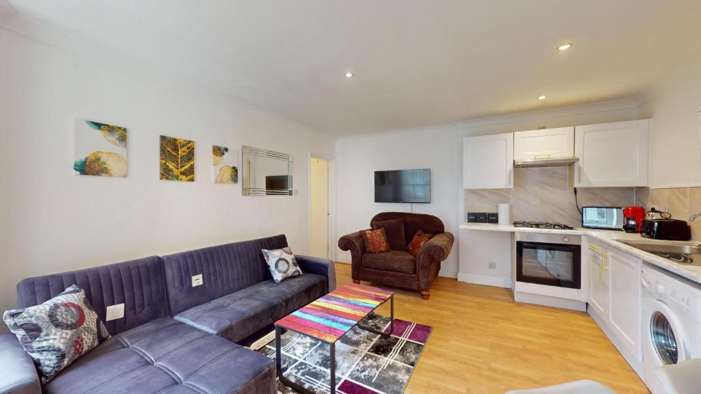 a living room with a couch and a kitchen at My Lovely Clapham Flat in London