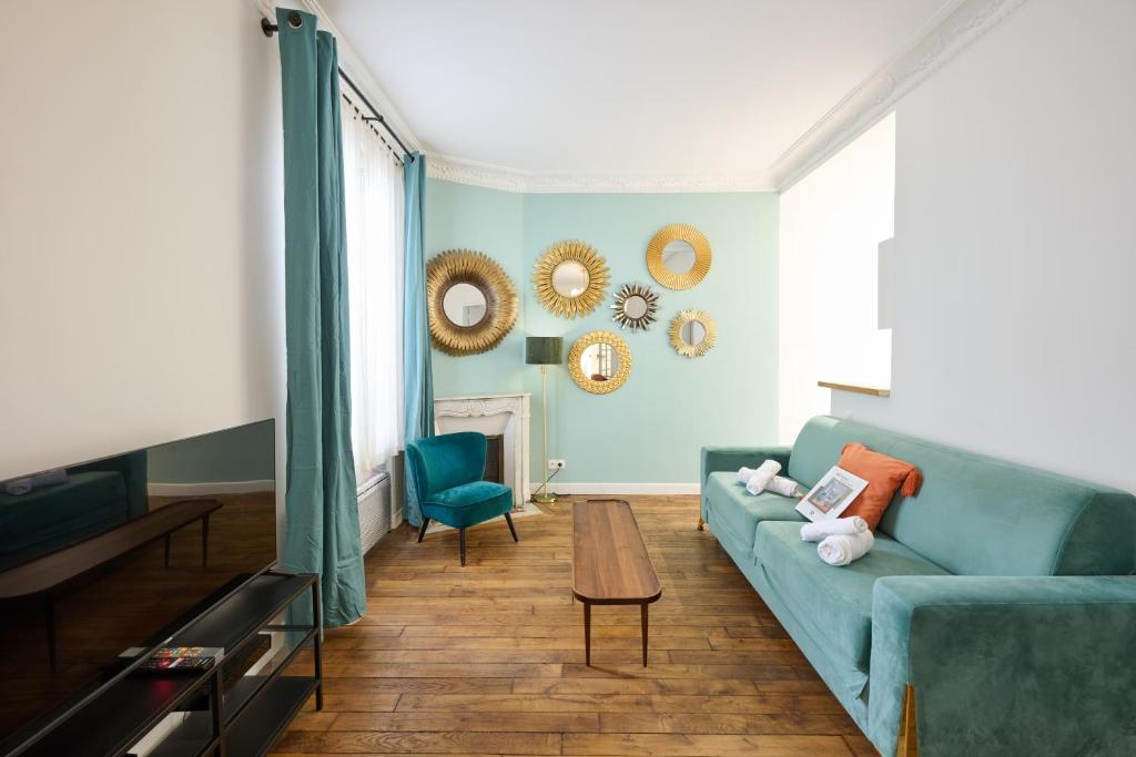 ein Wohnzimmer mit einem blauen Sofa und einem Tisch in der Unterkunft Très cosy 45m2, proche du parc des expositions in Paris