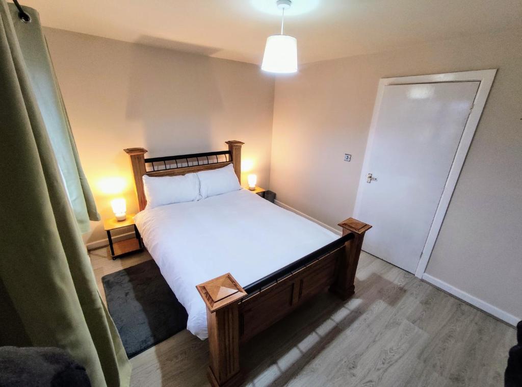 a bedroom with a bed with white sheets and two lamps at High Rigg House Bradford - Luxury Accomodation with Private Parking in Idle