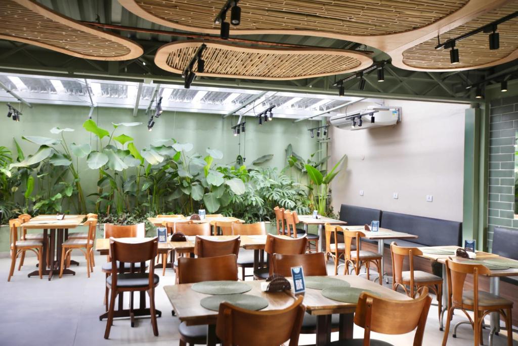 a dining room with tables and chairs and plants at Transamerica Executive Nova Paulista in São Paulo