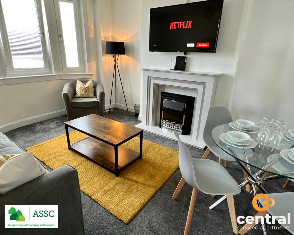 a living room with a table and a fireplace at 2 Bedroom Apartment by Central Serviced Apartments - Perfect for Short&Long Term Stays - Family Neighbourhood - Wi-Fi - FREE Street Parking - Sleeps 4 - 2 x King Beds - Smart TV in All Rooms - Modern - Weekly-Monthly Offers - Trade Stays - Close to A90 in Dundee