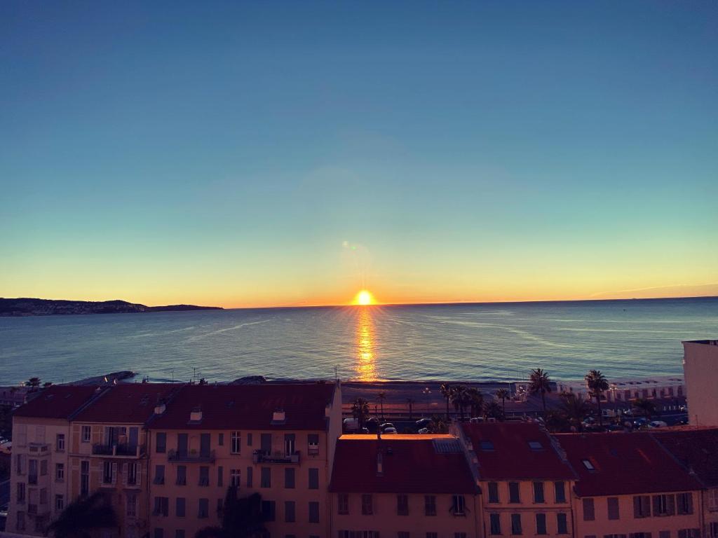 un coucher de soleil sur l'océan dans une ville dans l'établissement Magnifique vue mer la Californie, à Nice