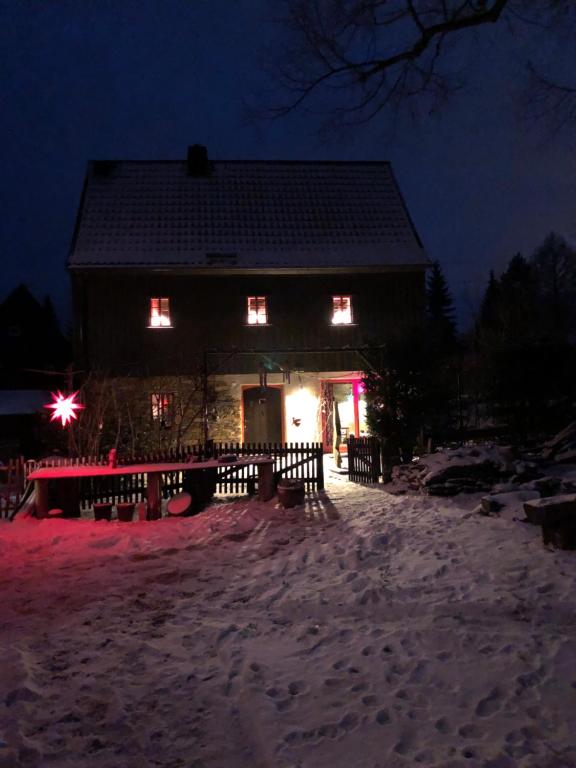 a house with lights on in the snow at night at Ferienhaus Lebenswerkstatthof in Mildenau