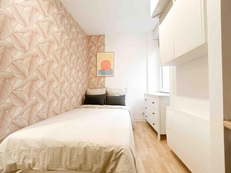 - une chambre avec un lit blanc et un mur dans l'établissement L'Echappée Nantaise, à Nantes