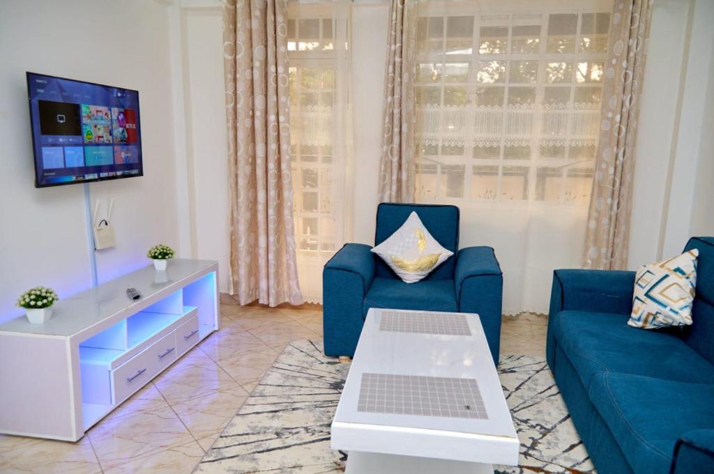 ein Wohnzimmer mit 2 blauen Sofas und einem TV in der Unterkunft Olivet Homes in Nanyuki