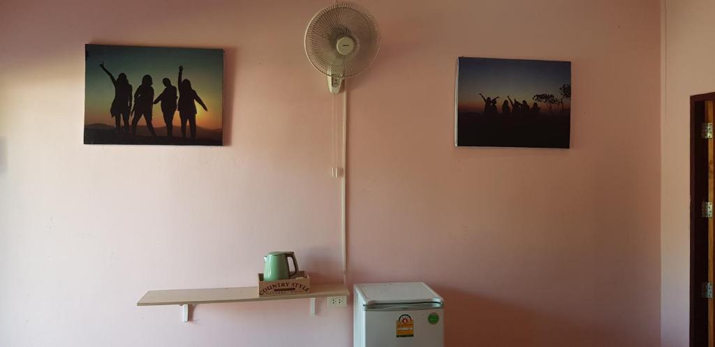 een kamer met drie foto's aan de muur en een koelkast bij โอคันทรี Ocountry in Khuang Nai