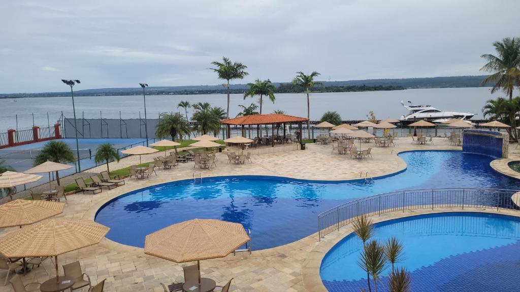 a resort with a large pool with tables and umbrellas at Premier Residence in Brasília