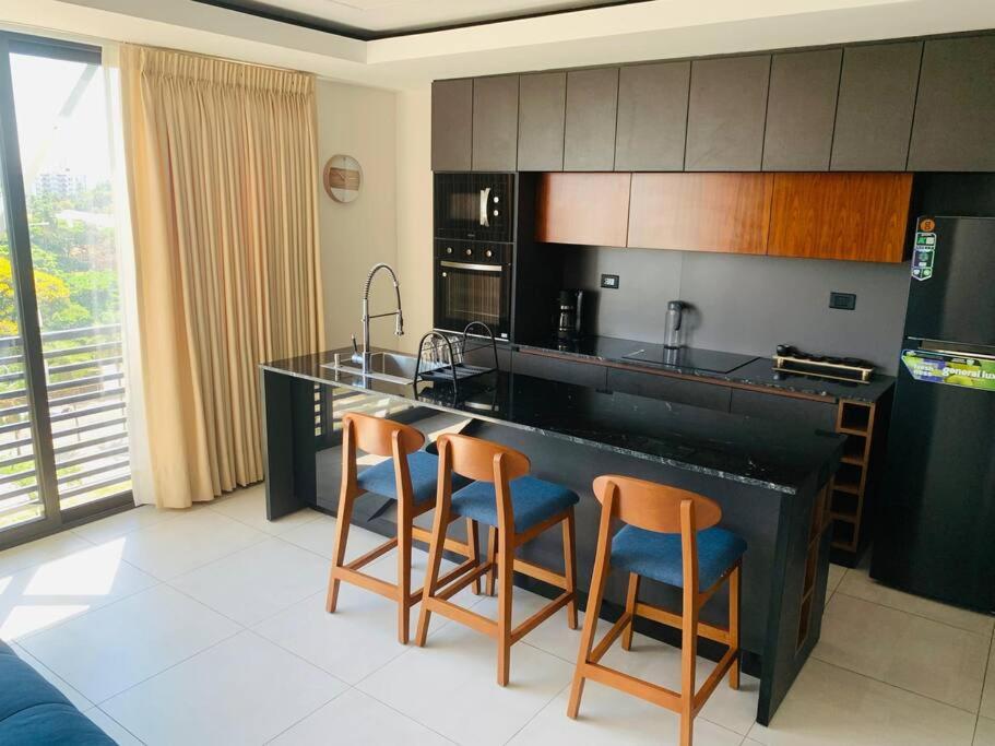 a kitchen with a black counter and two bar stools at Departamento con vista de lujo in Santa Cruz de la Sierra