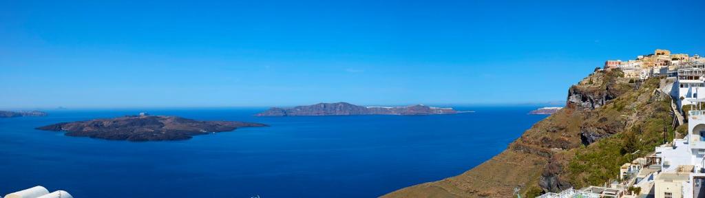 a view of the ocean with buildings on a mountain at EDGE ON VOLCANO SUITES in Fira