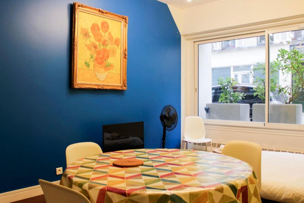 une salle à manger avec une table et un mur bleu dans l'établissement Colored Appt To Beaugrenelle, à Paris