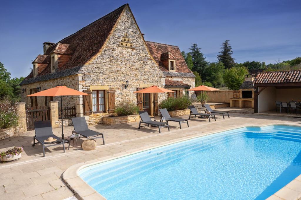 ein Haus mit einem Pool vor einem Haus in der Unterkunft Villa en pierre 10 pers, piscine chauffée in Saint-Amand-de-Coly