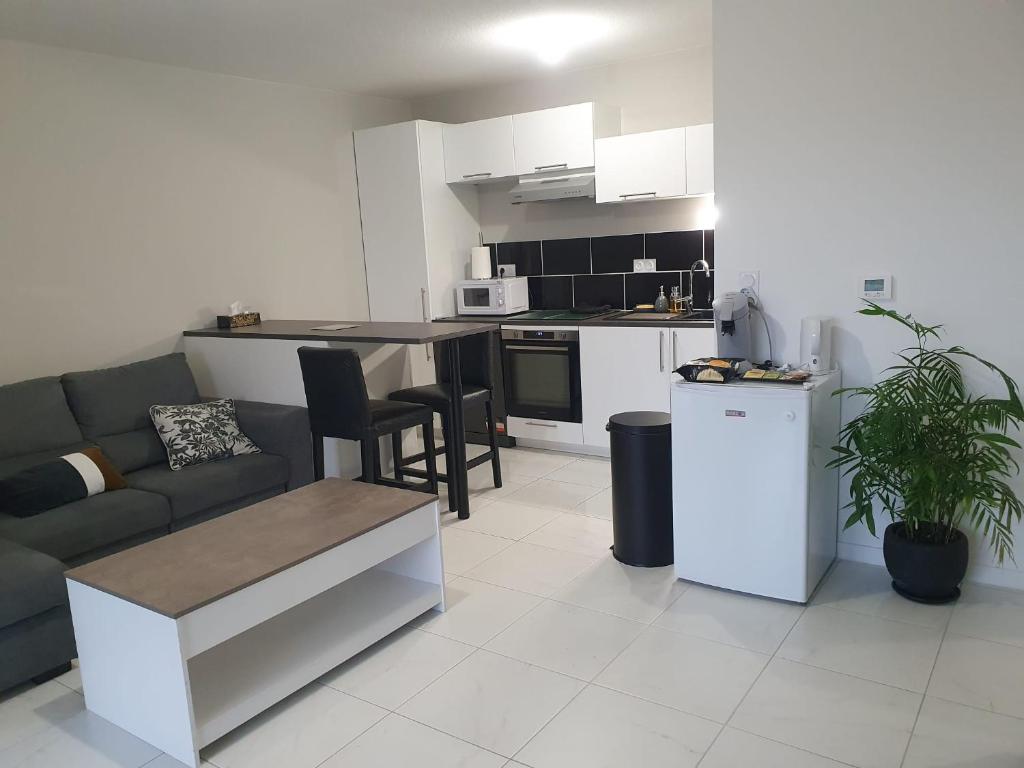 uma sala de estar com um sofá e uma cozinha em Appartement avec 2 chambres, un parking privé, une terrasse, à Floirac-Arkéa Arena Bordeaux em Floirac