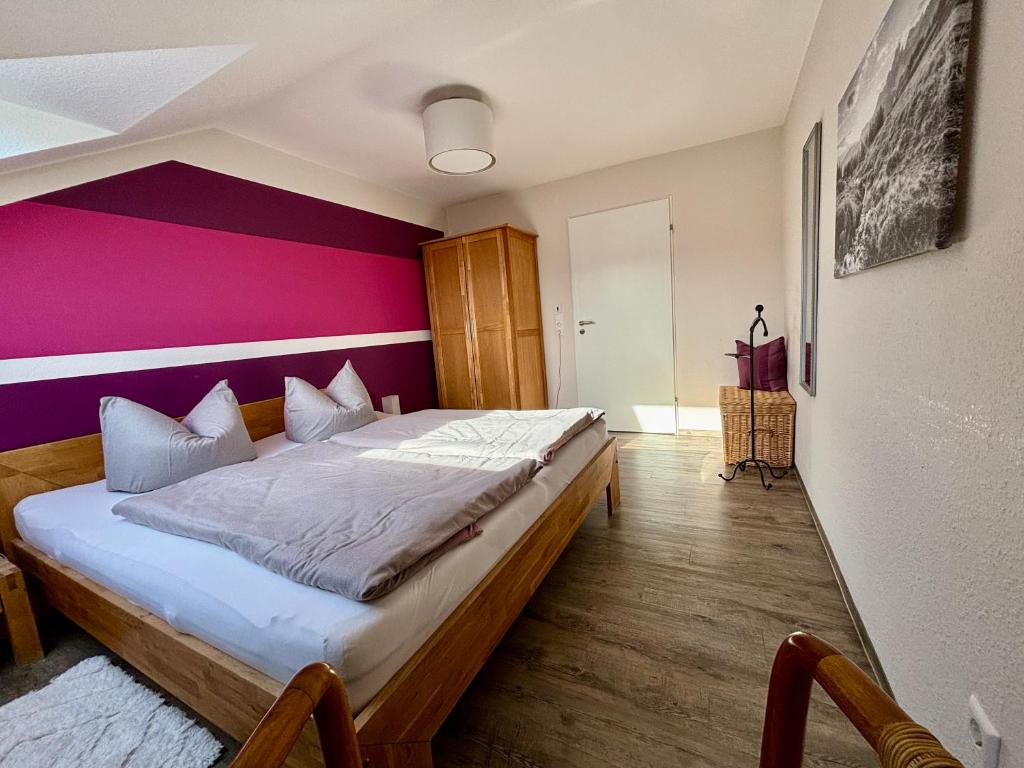 ein Schlafzimmer mit einem großen Bett mit einer lila Wand in der Unterkunft Ferienwohnung Felderhaldeblick in Isny im Allgäu