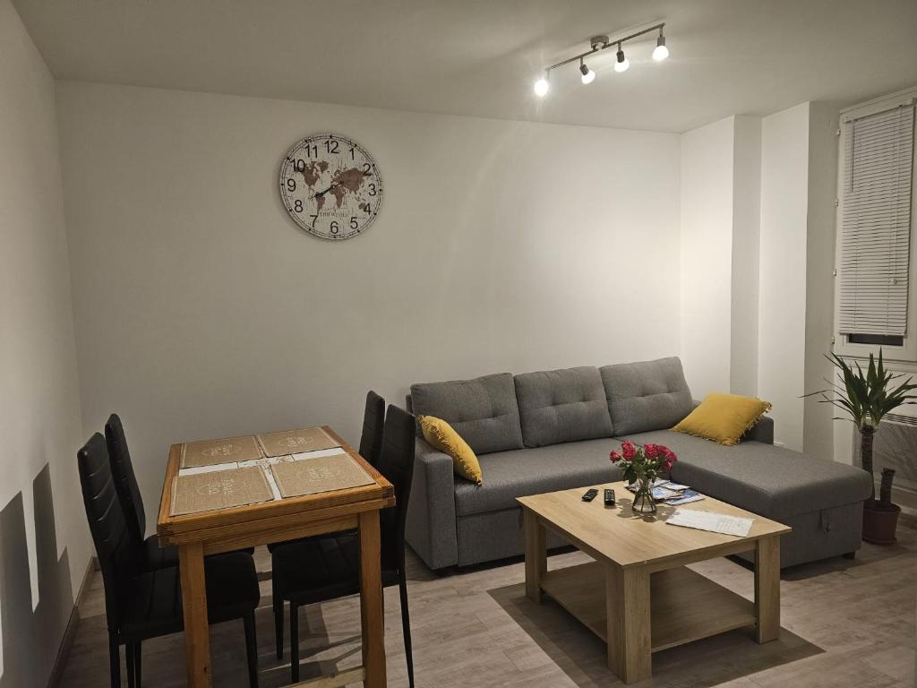 a living room with a couch and a table and a clock at Joli appartement en face de lac in Nantua