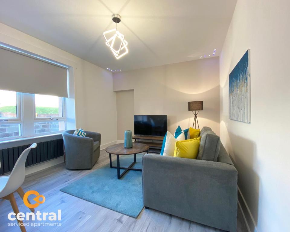 a living room with a couch and a table at 2 Bedroom Apartment by Central Serviced Apartments - Monthly Bookings Welcome - FREE Street Parking - WiFi - Smart TV - Ground Level - Family Neighbourhood - Sleeps 4 - 1 Double Bed - 2 Single Beds - Heating 24-7 - Trade Stays - Weekly & Monthly Offers in Dundee