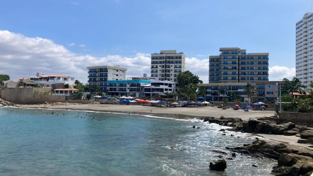 a beach with a group of people in the water at Playa el Mansito Apartamento Ocean Sun in Punta Blanca