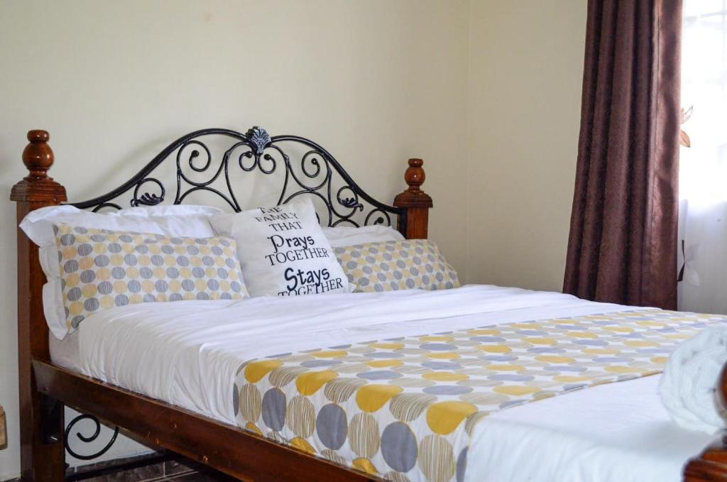sypialnia z łóżkiem z drewnianym zagłówkiem i poduszkami w obiekcie ELDORET STAYS w mieście Eldoret