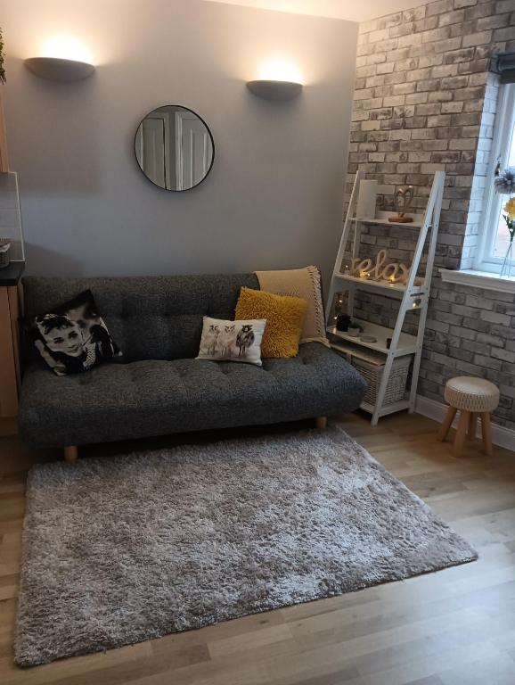 uma sala de estar com um sofá e um espelho em Bijou Apartment em Berwick-Upon-Tweed