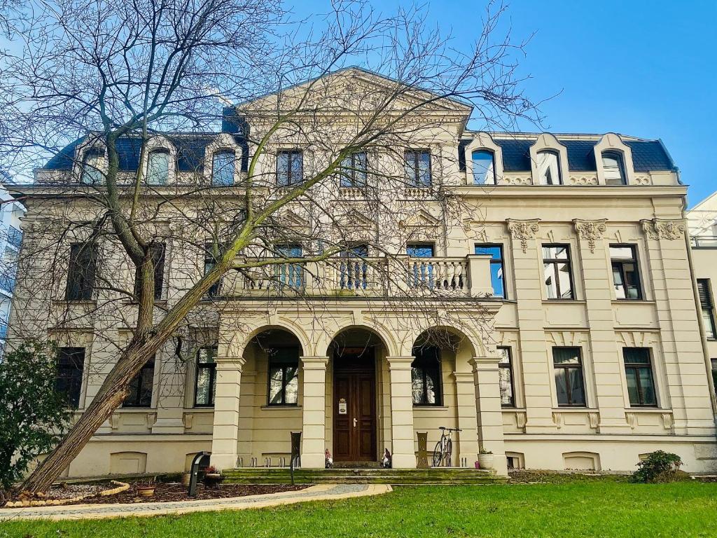 ein großes Gebäude mit einem Baum davor in der Unterkunft Downtown Apartments Leipzig in Leipzig