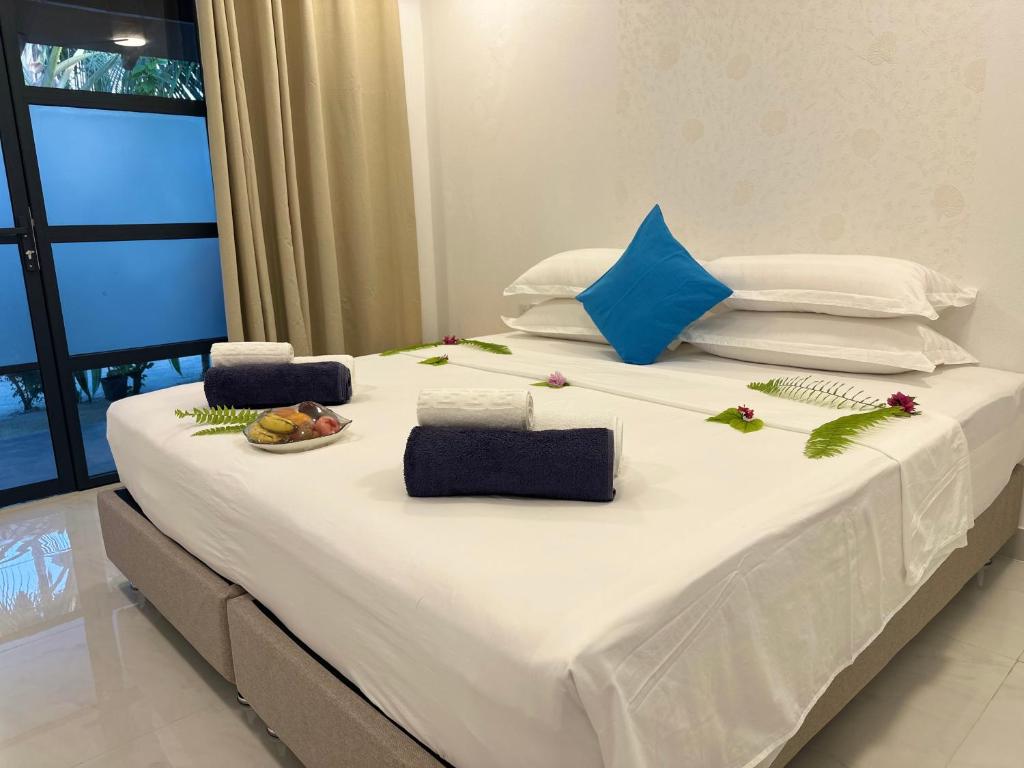 a large bed with white sheets and flowers on it at Boli Villa Thoddoo in Thoddoo