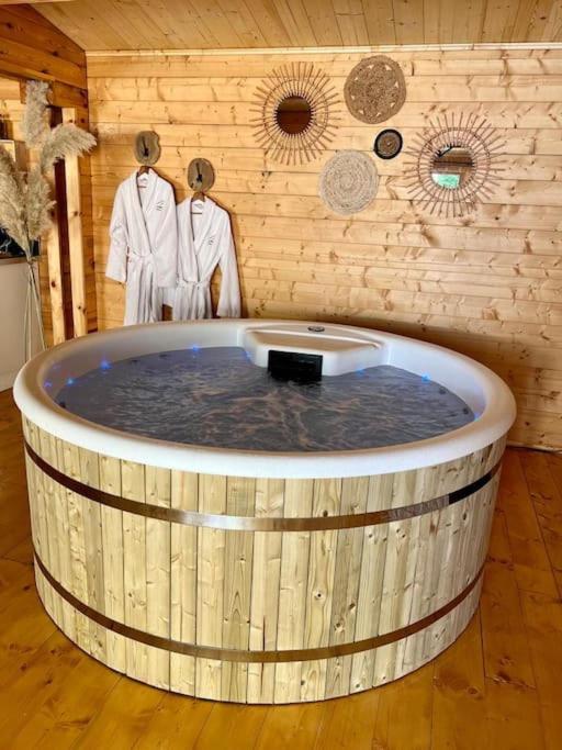 - un bain à remous dans une pièce avec des vêtements sur des crochets dans l'établissement L'Enseigne -Location de 2 chalets privatifs avec Spa, à Venizel