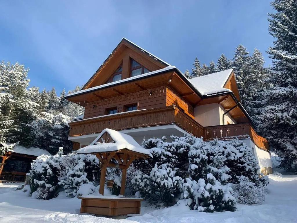 una casa ricoperta di neve di fronte agli alberi di Chata Šafran a Liptovský Ján