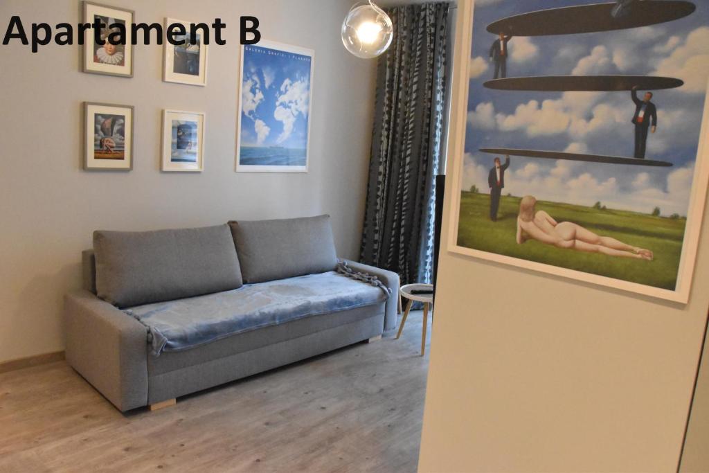 ein Wohnzimmer mit einem Sofa und einem Gemälde an der Wand in der Unterkunft Apartament za 400m Plaża Sopot in Sopot